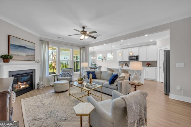 living room featuring light hardwood / wood-style flooring, ceiling fan, and ornamental molding