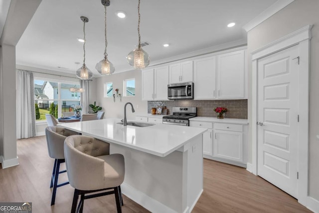 kitchen featuring white cabinets, decorative light fixtures, sink, and stainless steel appliances