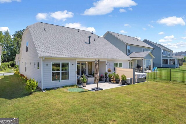 back of property featuring a yard, a hot tub, and a patio area