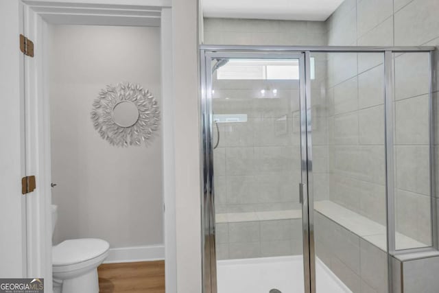 bathroom featuring wood-type flooring, toilet, and a shower with door