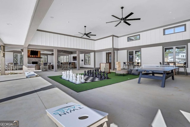 interior space with an outdoor stone fireplace, ceiling fan, concrete flooring, and a towering ceiling