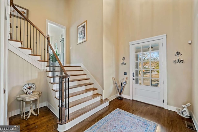 foyer entrance with a towering ceiling and dark wood-type flooring