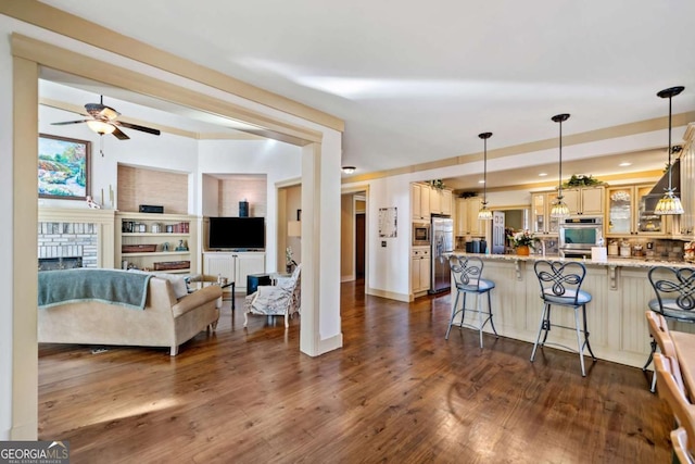 kitchen featuring a kitchen bar, stainless steel appliances, built in features, a fireplace, and hanging light fixtures