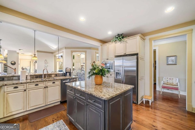 kitchen featuring sink, stainless steel appliances, hanging light fixtures, and cream cabinets