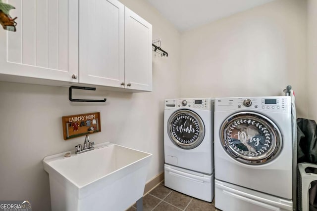 clothes washing area with cabinets, separate washer and dryer, dark tile patterned flooring, and sink