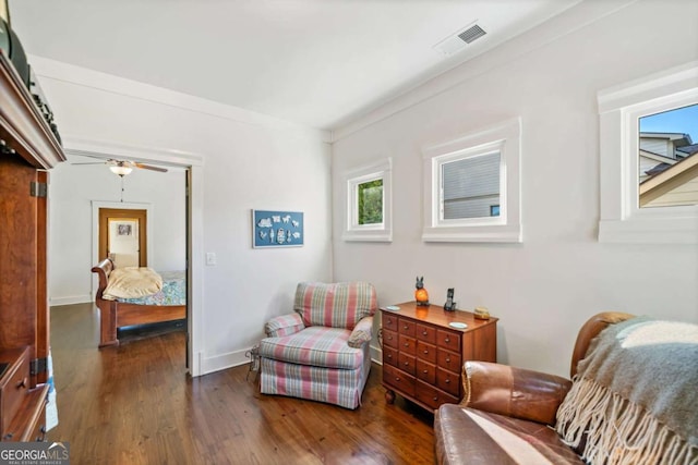 living area with crown molding, ceiling fan, and dark hardwood / wood-style floors