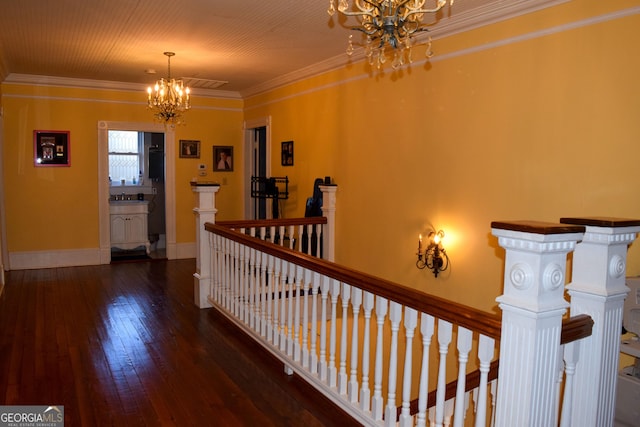 corridor with dark hardwood / wood-style flooring, ornamental molding, and an inviting chandelier