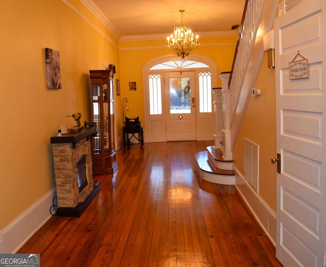 entryway with a fireplace, dark hardwood / wood-style floors, an inviting chandelier, and crown molding