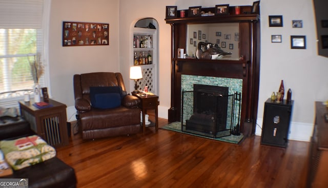 living room featuring a tiled fireplace, hardwood / wood-style floors, and built in shelves