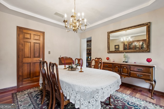 dining area featuring an inviting chandelier, dark wood-type flooring, and a tray ceiling