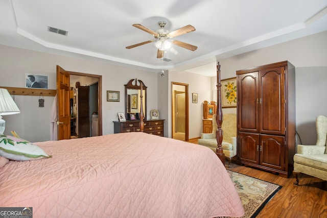 bedroom featuring ceiling fan, light hardwood / wood-style flooring, and a tray ceiling