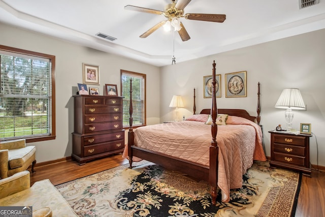 bedroom featuring ceiling fan, a raised ceiling, and light hardwood / wood-style flooring