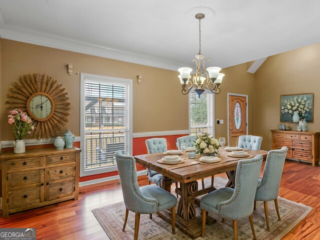 dining area featuring an inviting chandelier, ornamental molding, and light wood-type flooring