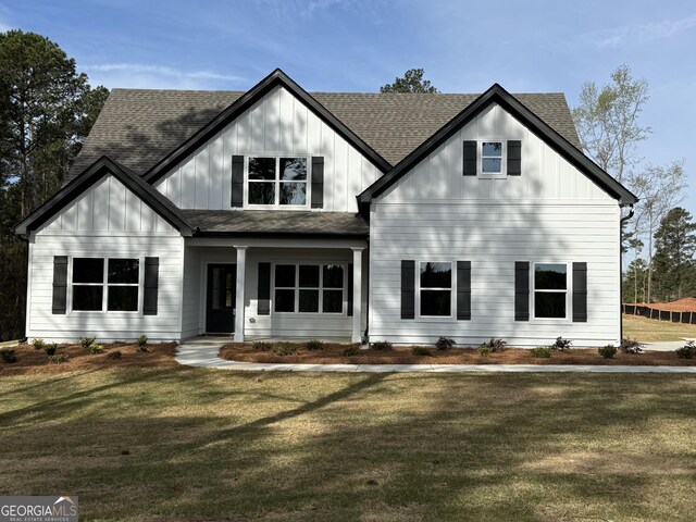 modern inspired farmhouse featuring board and batten siding, roof with shingles, and a front lawn