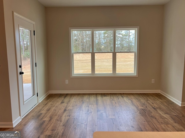 empty room featuring plenty of natural light, baseboards, and wood finished floors