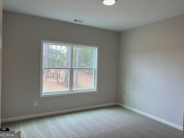 empty room with carpet floors, baseboards, and visible vents