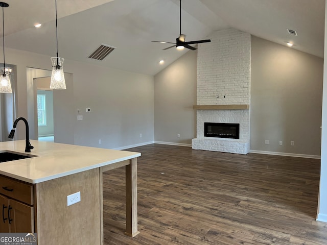 kitchen featuring dark wood-type flooring, a fireplace, a sink, visible vents, and open floor plan