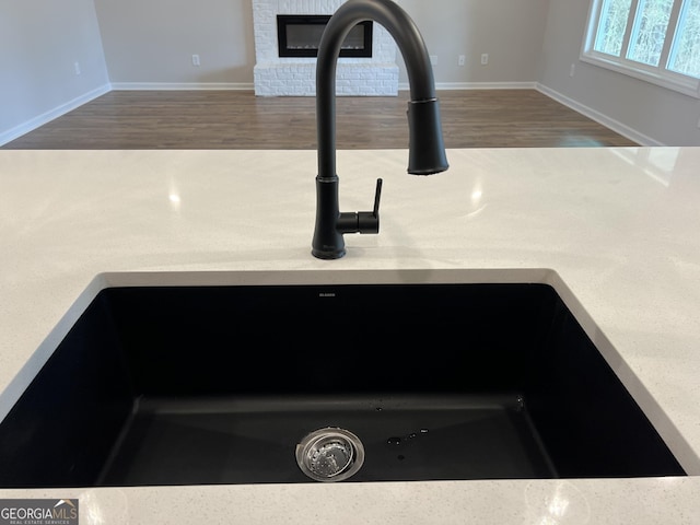 details featuring a brick fireplace, light countertops, a sink, and wood finished floors