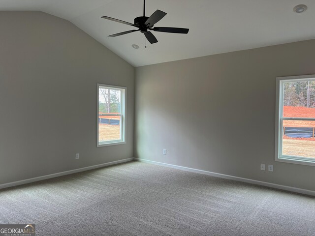 carpeted empty room with baseboards, vaulted ceiling, a ceiling fan, and a healthy amount of sunlight
