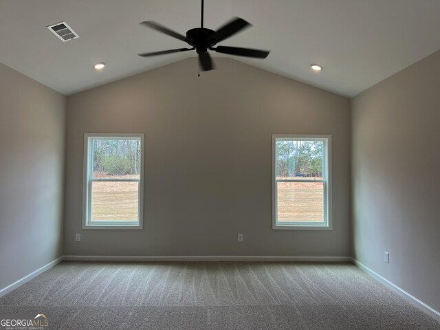 carpeted spare room with baseboards, visible vents, a ceiling fan, and vaulted ceiling
