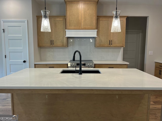 kitchen featuring custom range hood, hanging light fixtures, a sink, light countertops, and backsplash