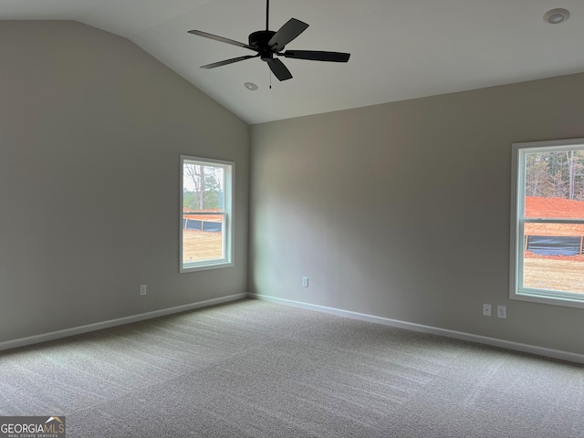 carpeted spare room featuring lofted ceiling, plenty of natural light, baseboards, and a ceiling fan