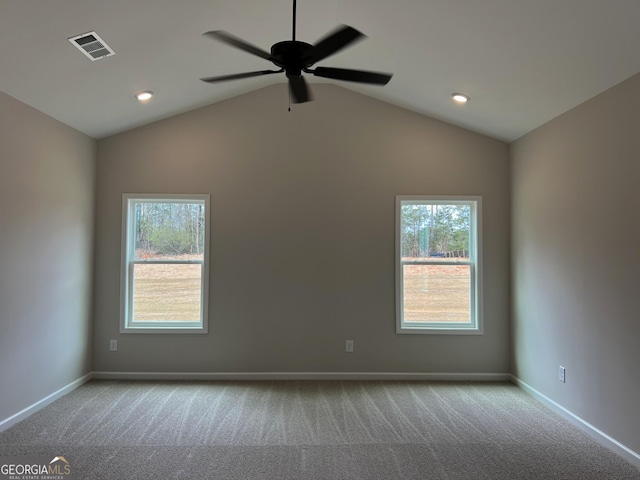 carpeted empty room with a healthy amount of sunlight, visible vents, and lofted ceiling