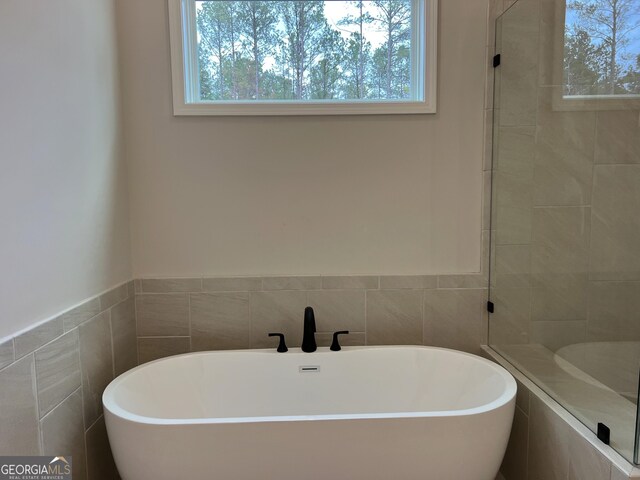 bathroom featuring tile walls and a freestanding bath