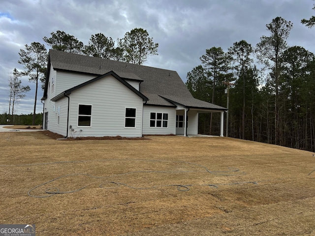 view of front facade featuring a shingled roof and a front yard