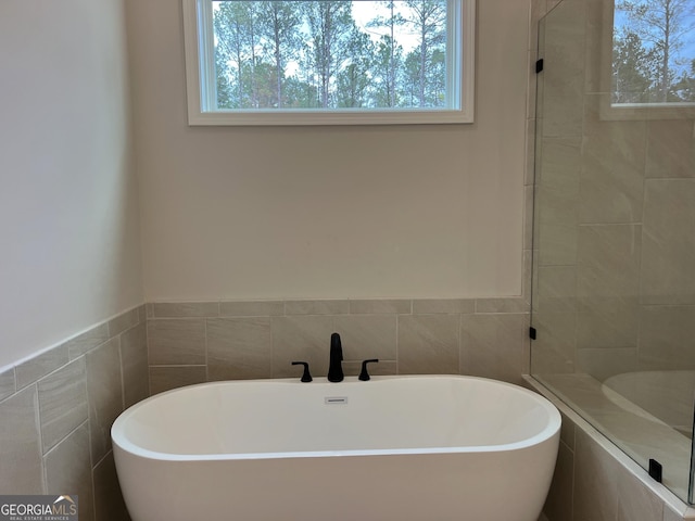 bathroom with tiled shower, a freestanding bath, and tile walls