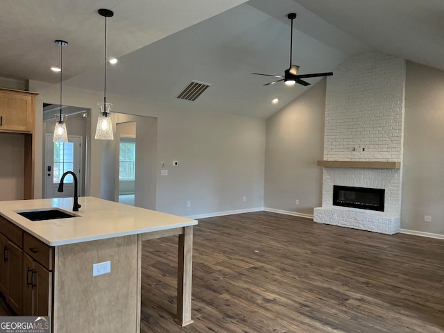 kitchen with visible vents, open floor plan, dark wood-style flooring, a fireplace, and a sink