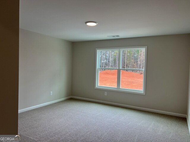 spare room featuring baseboards, visible vents, and carpet flooring