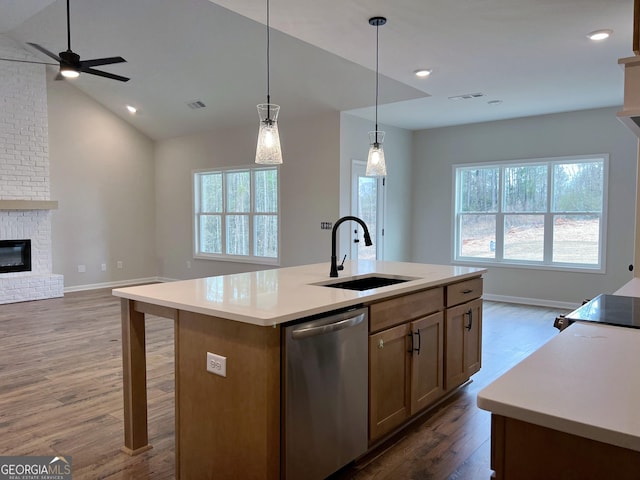 kitchen with a sink, visible vents, open floor plan, stainless steel dishwasher, and a brick fireplace