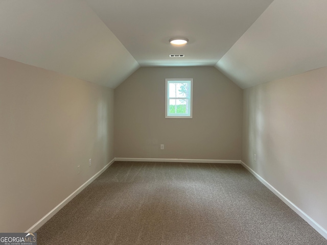 additional living space with lofted ceiling, baseboards, visible vents, and carpet flooring