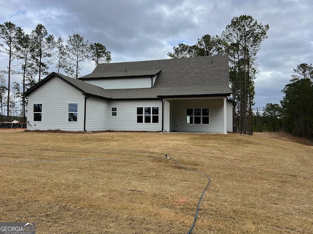 back of property with a yard and a shingled roof