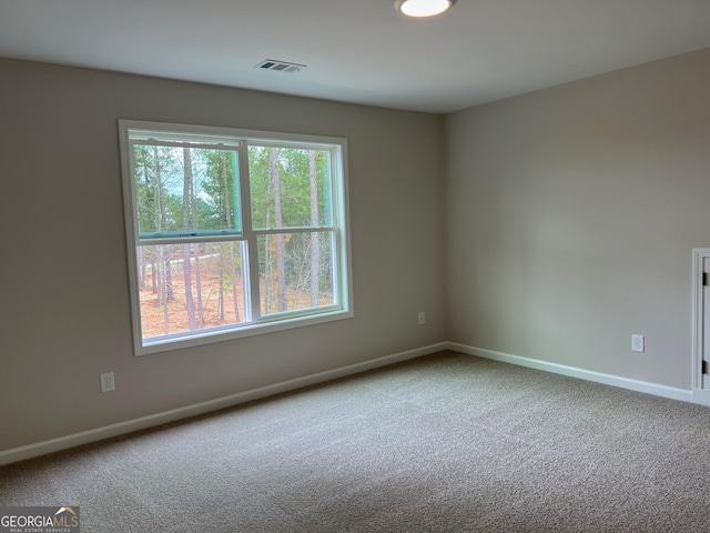 carpeted spare room featuring visible vents and baseboards