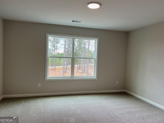 unfurnished room with carpet floors, visible vents, and baseboards