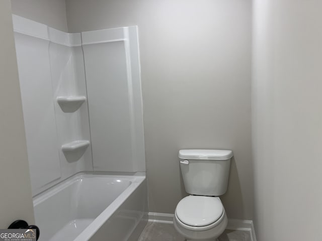 bathroom featuring toilet, shower / bath combination, and baseboards