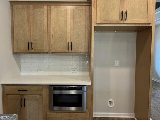 kitchen with baseboards, light countertops, stainless steel oven, and tasteful backsplash