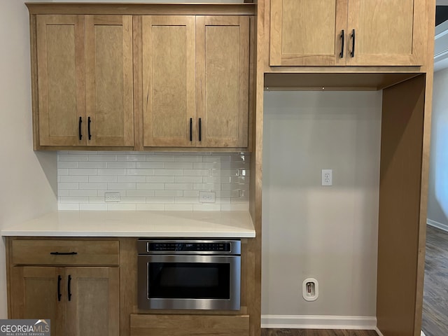 kitchen featuring stainless steel oven, baseboards, light countertops, tasteful backsplash, and brown cabinetry