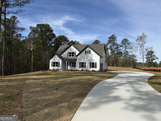 modern inspired farmhouse featuring driveway, a front yard, and board and batten siding
