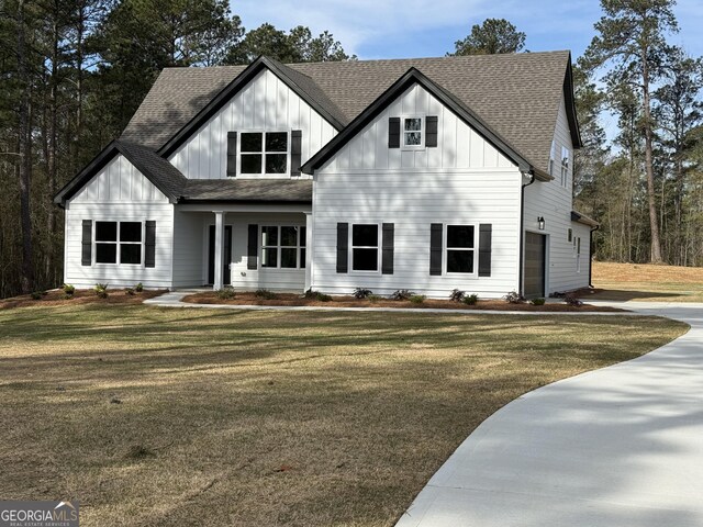 modern farmhouse with board and batten siding, a front yard, and a shingled roof