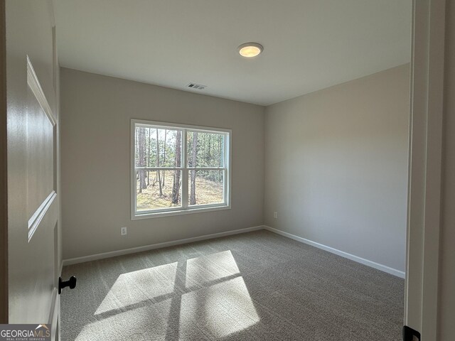 spare room with carpet, baseboards, and visible vents
