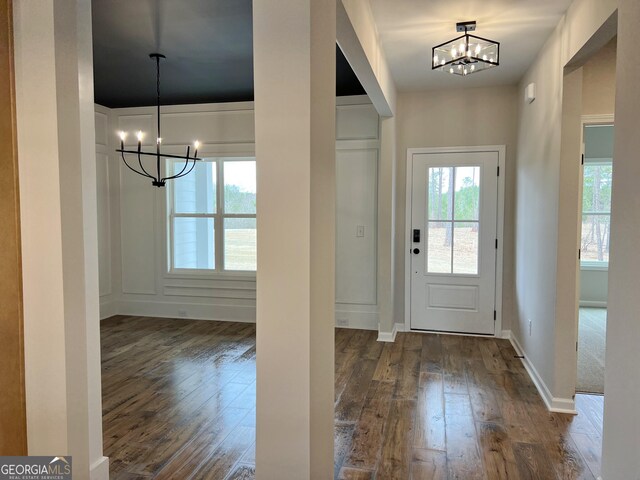 entryway featuring baseboards, dark wood-style flooring, a wealth of natural light, and a notable chandelier