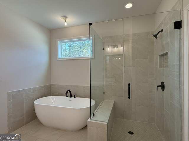 bathroom with tile walls, a freestanding tub, and a shower stall
