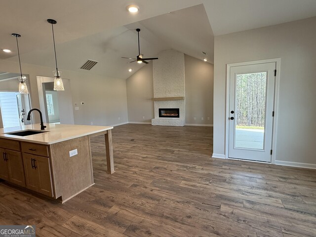 kitchen featuring dark wood-type flooring, visible vents, a fireplace, and a sink