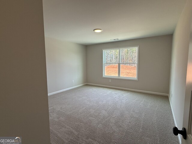 carpeted spare room featuring baseboards and visible vents