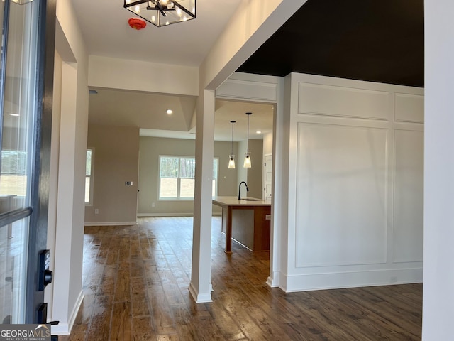 foyer with a chandelier, dark wood-type flooring, baseboards, and a decorative wall