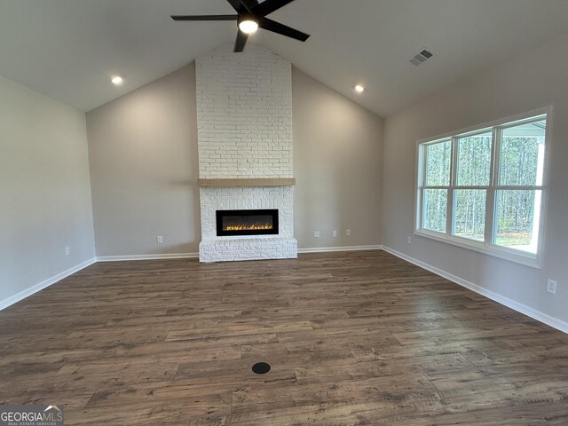 unfurnished living room featuring a brick fireplace, dark wood-style flooring, baseboards, visible vents, and a ceiling fan