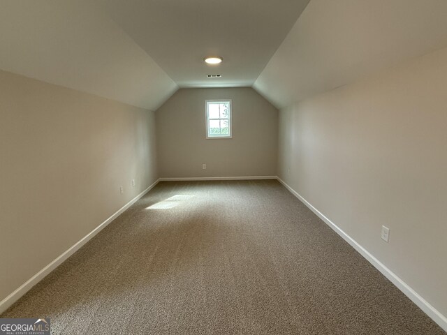 additional living space featuring baseboards, vaulted ceiling, and visible vents